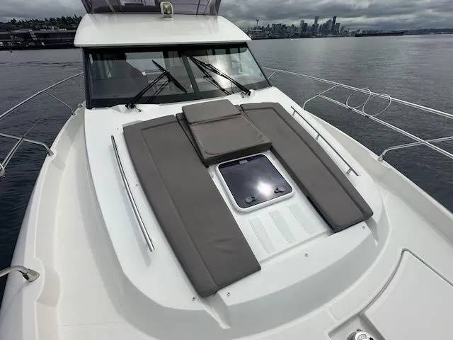 R & R Yacht Photos Pics 2015 Prestige 420 yacht with cushioned deck, overlooking a city skyline on a cloudy day.