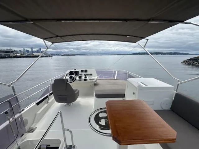 R & R Yacht Photos Pics Flybridge of 2015 Prestige 420 yacht with helm, seating, and table, overlooking calm waters.