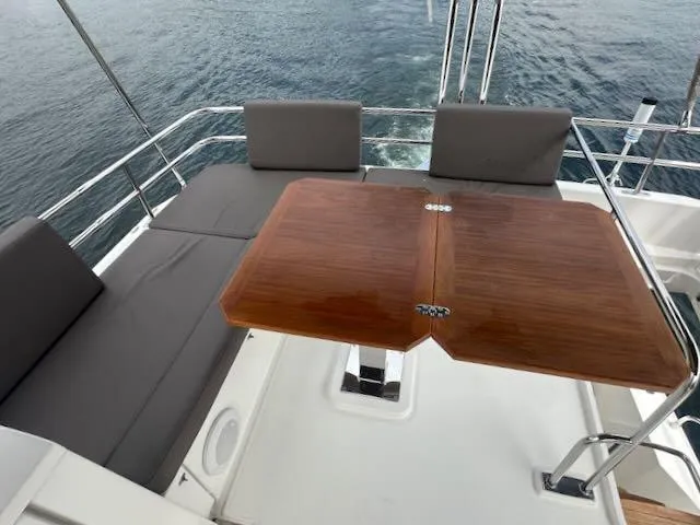R & R Yacht Photos Pics Flybridge seating area on 2015 Prestige 420 yacht with wooden table and gray cushions.