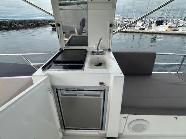R & R Yacht Photos Pics Outdoor kitchenette on a 2015 Prestige 420 yacht with sink, stove, and mini-fridge.