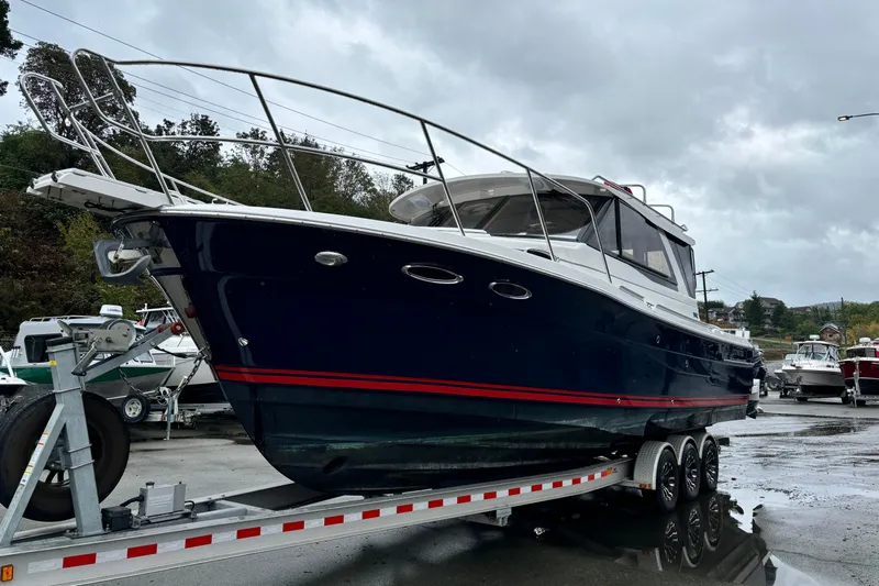  Yacht Photos Pics 2019 Cutwater C-302 Coupe boat on trailer, dark blue hull, overcast sky.