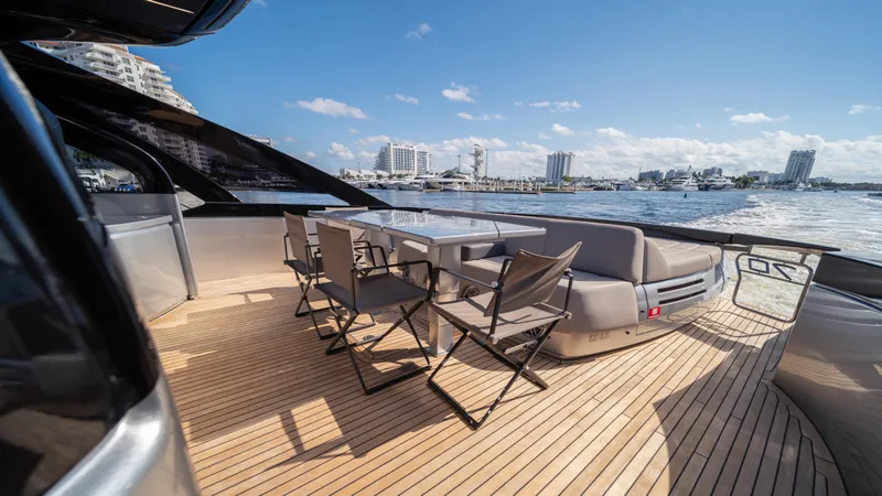 "liquid" Yacht Photos Pics Luxurious 2020 Pershing 70 yacht deck with seating, overlooking a scenic waterfront.