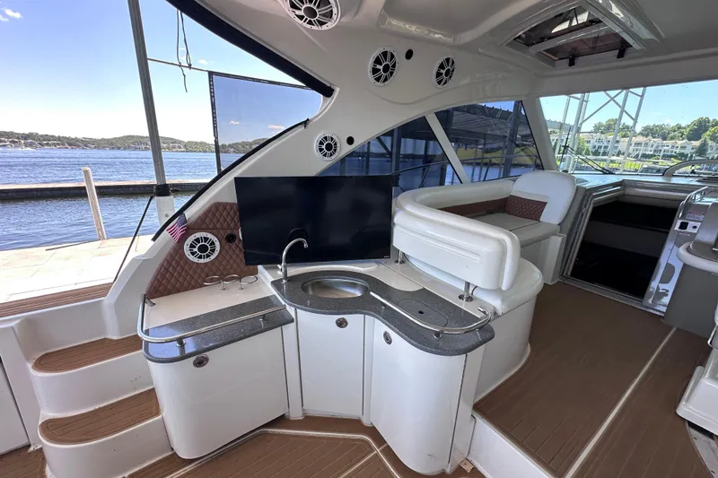  Yacht Photos Pics 2005 Sea Ray 48 Sundancer yacht interior with seating, sink, and TV, docked by the water.