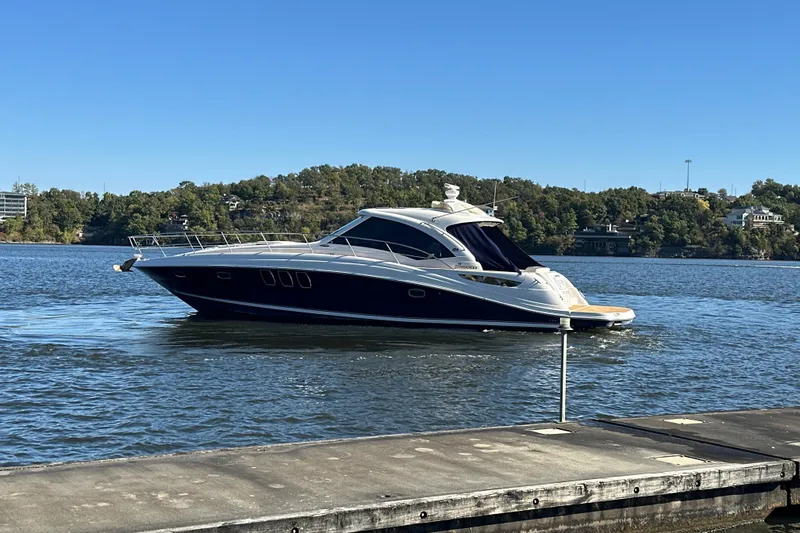  Yacht Photos Pics 2005 Sea Ray 48 Sundancer yacht cruising on a serene lake under clear blue skies.
