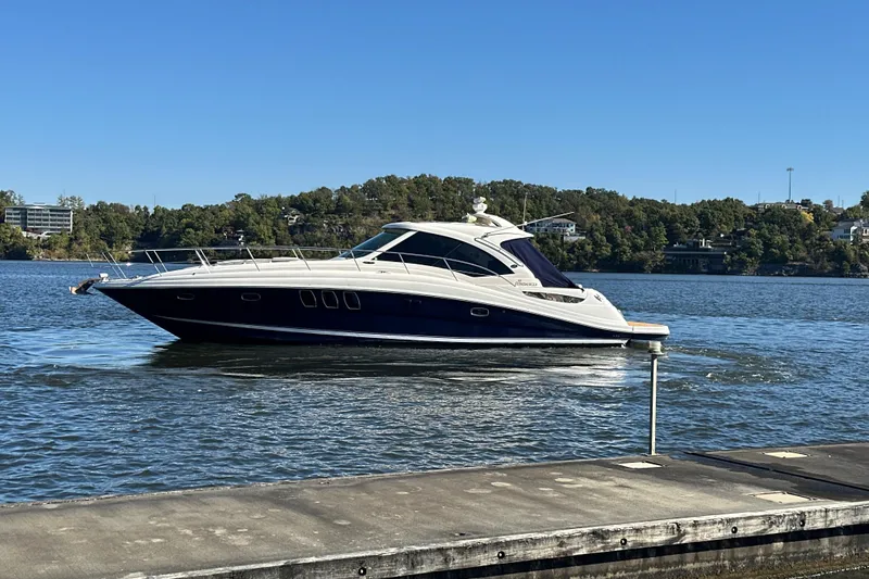  Yacht Photos Pics 2005 Sea Ray 48 Sundancer yacht cruising on a serene lake under clear blue skies.