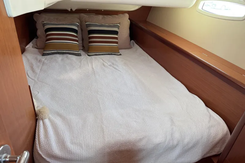 Eos Yacht Photos Pics Cozy cabin interior of 2008 Beneteau Oceanis 40 with striped pillows and white bedding.