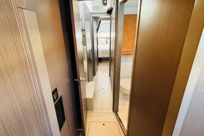  Yacht Photos Pics Narrow hallway inside 2022 Leopard 45 yacht, featuring modern wood paneling and compact bathroom.