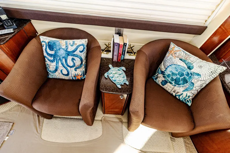  Yacht Photos Pics Two brown chairs with ocean-themed pillows and books on a 2009 Meridian 391 Sedan.