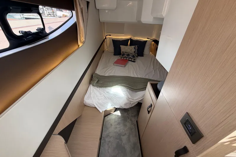  Yacht Photos Pics Cozy cabin interior of 2026 Jeanneau TH38 with bed, pillows, and window view.