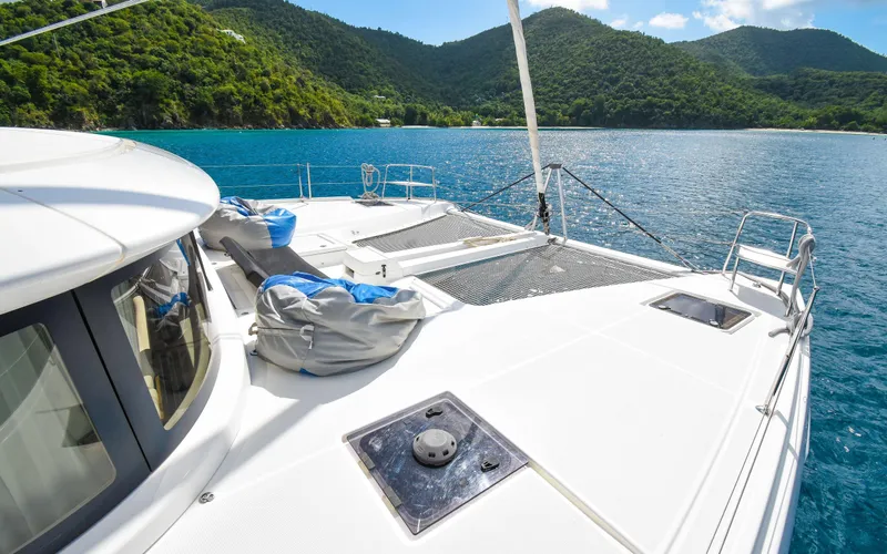 Celavie Yacht Photos Pics 2021 Lagoon 46 catamaran on serene blue waters with lush green hills.