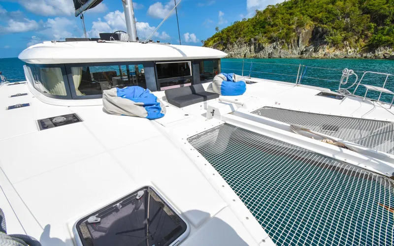 Celavie Yacht Photos Pics 2021 Lagoon 46 catamaran on turquoise water, featuring spacious deck and netting.