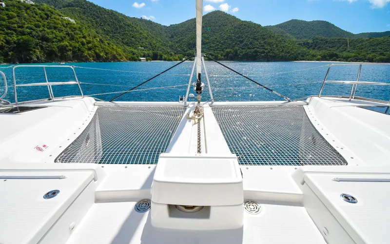 Celavie Yacht Photos Pics 2021 Lagoon 46 catamaran on serene water with lush green hills in the background.