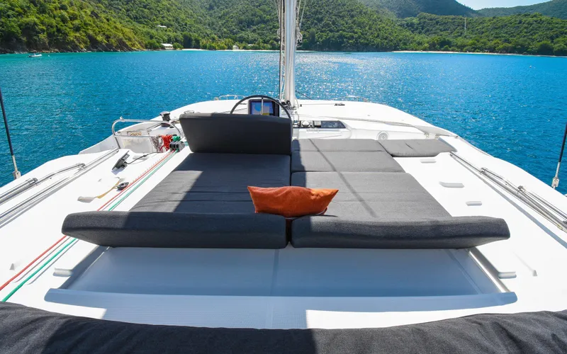 Celavie Yacht Photos Pics Luxurious Lagoon 46 catamaran deck with sunbeds, overlooking serene blue waters and lush green hills.