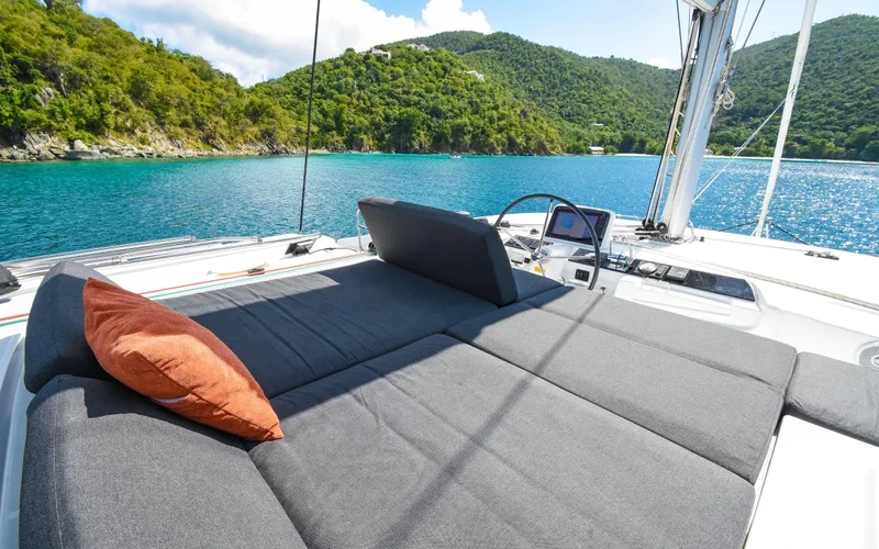 Celavie Yacht Photos Pics 2021 Lagoon 46 yacht with sunbed, scenic ocean view, and lush green hills.