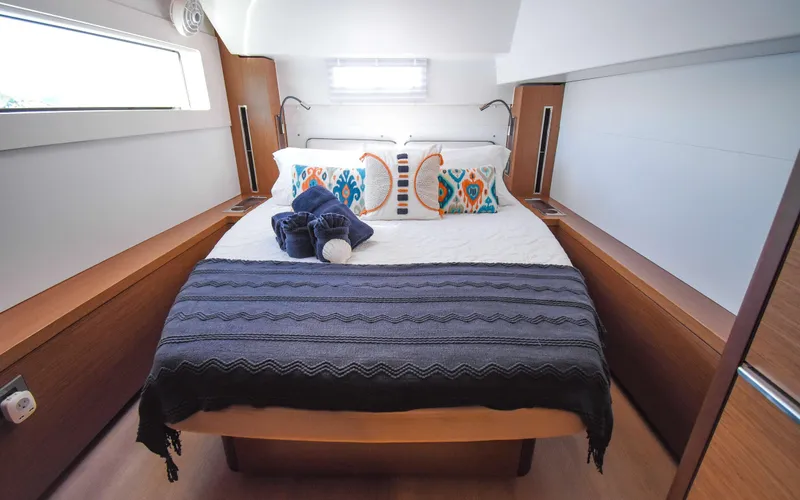 Celavie Yacht Photos Pics Luxurious bedroom interior of 2021 Lagoon 46 yacht with modern decor and cozy bedding.