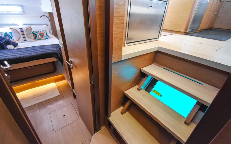 Celavie Yacht Photos Pics Interior of 2021 Lagoon 46 yacht, featuring cozy bedroom and modern wooden staircase.