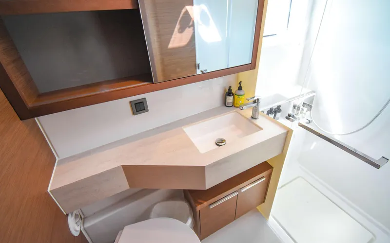 Celavie Yacht Photos Pics Modern bathroom interior of 2021 Lagoon 46 yacht, featuring sleek sink and shower area.
