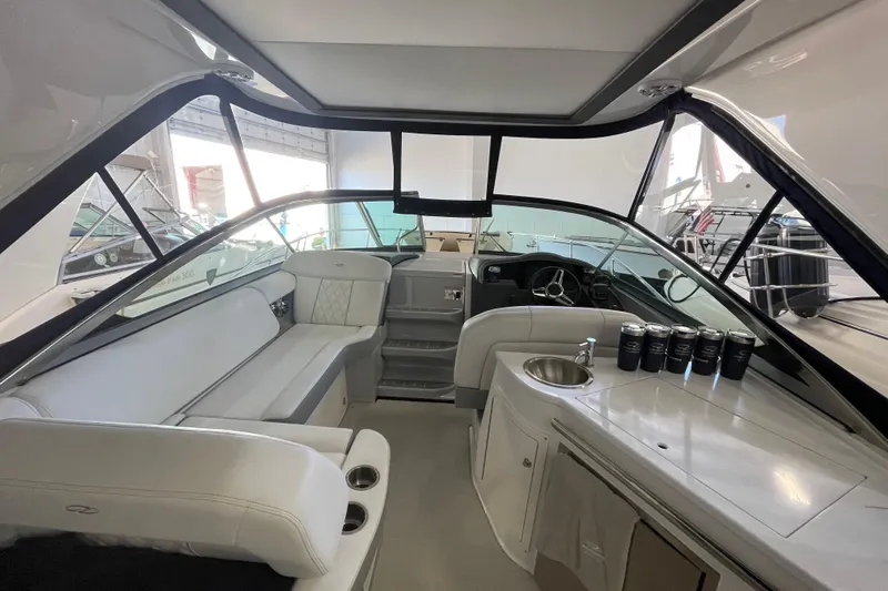  Yacht Photos Pics 2023 Regal 33 Express boat interior with seating, sink, and helm in a showroom.