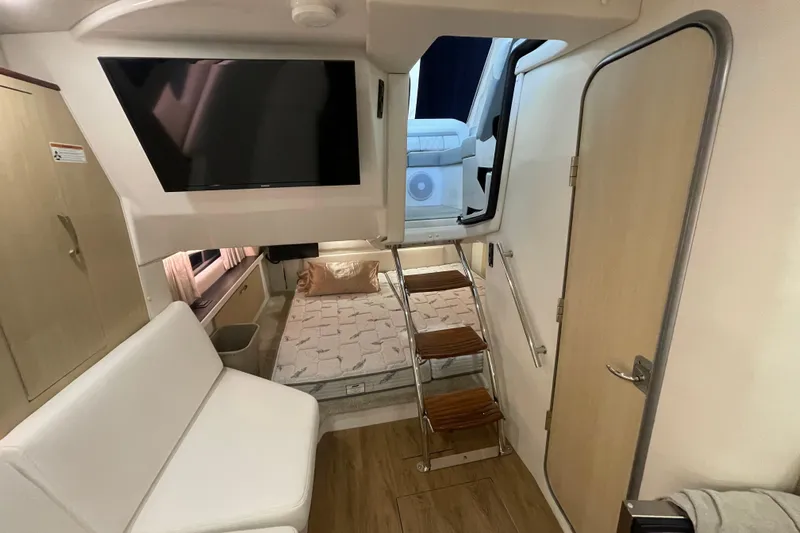  Yacht Photos Pics 2023 Regal 33 Express interior with TV, bed, and stairs in a modern cabin setting.