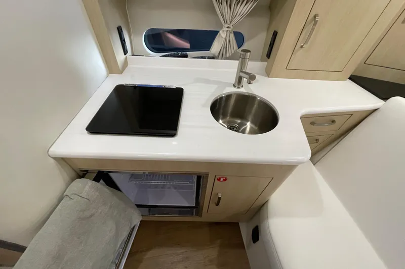  Yacht Photos Pics 2023 Regal 33 Express yacht interior kitchen with sink, stove, and mini fridge.