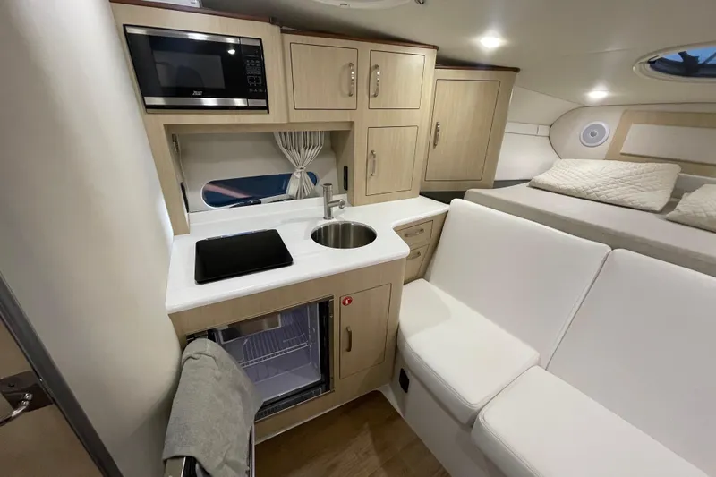  Yacht Photos Pics 2023 Regal 33 Express interior with kitchenette, microwave, sink, and seating area.