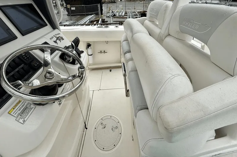  Yacht Photos Pics 2015 Boston Whaler 280 Outrage helm with steering wheel and cushioned seating.