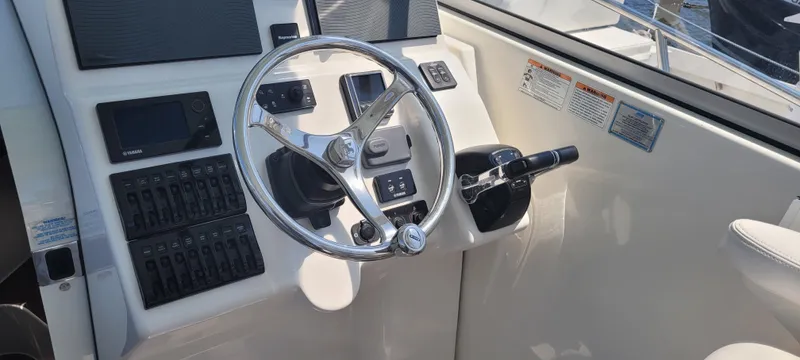 Dos Suenos Yacht Photos Pics Control panel of a 2015 Century 30 boat with steering wheel and navigation instruments.