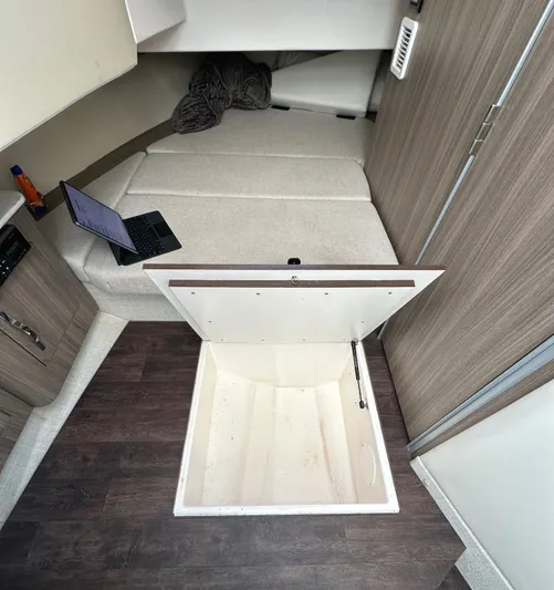  Yacht Photos Pics 2020 Regal 33 SAV cabin interior with open storage hatch and laptop on bed.