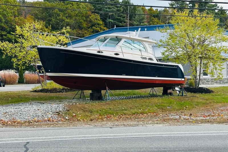 Amanda Yacht Photos Pics 2024 Back Cove 34O boat displayed outdoors on stands, surrounded by trees.