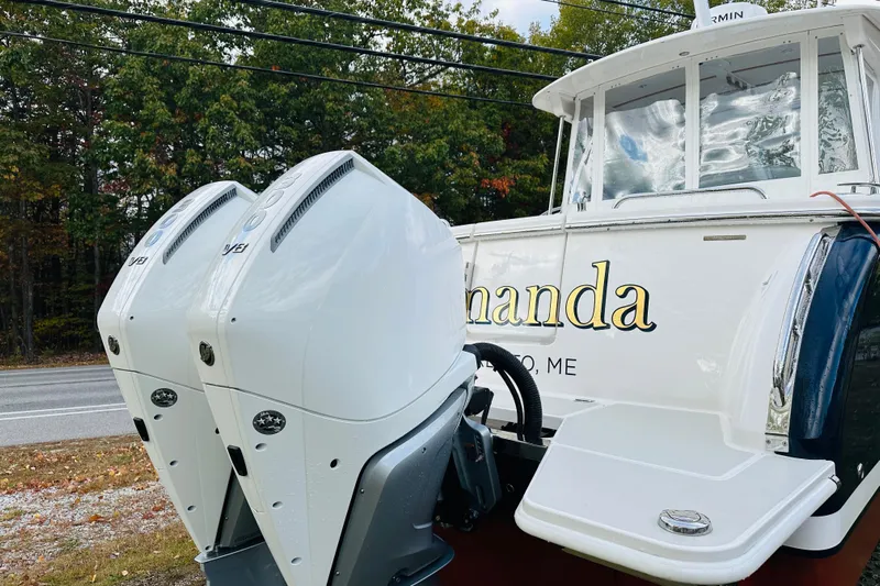 Amanda Yacht Photos Pics 2024 Back Cove 34O boat with dual outboard engines, docked near a wooded area.