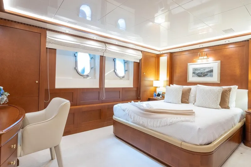 Oceanos Yacht Photos Pics Luxurious Mondomarine motor yacht bedroom, 2006 model, featuring elegant wood paneling and plush bedding.