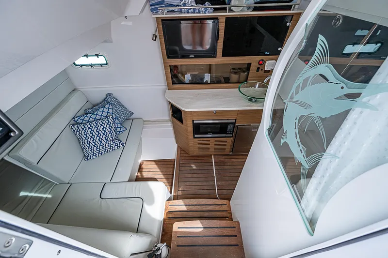Riptide Yacht Photos Pics Interior of 2018 Everglades 435 Center Console with seating, kitchenette, and decorative glass panel.