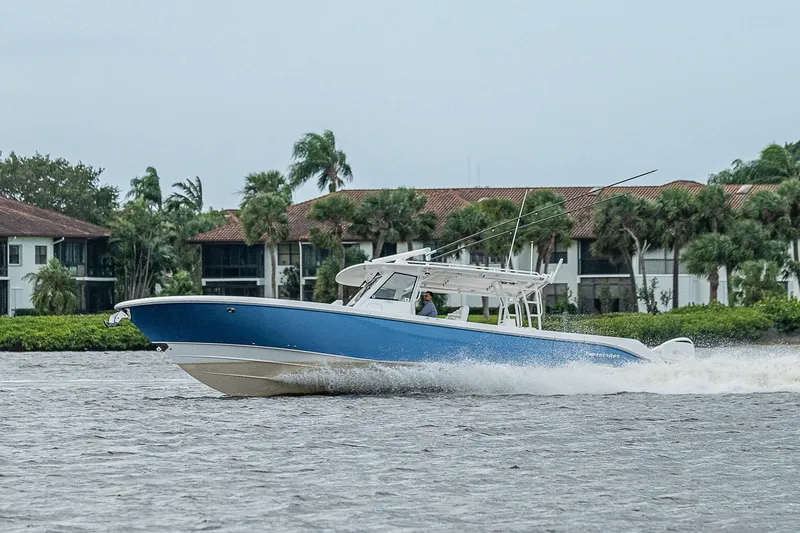 Riptide Yacht Photos Pics 2018 Everglades 435 Center Console boat cruising on water near waterfront homes.