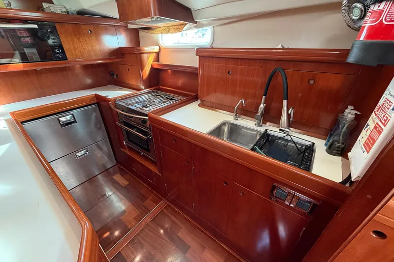 Nae Hassle Yacht Photos Pics Luxurious 2004 Beneteau 57 yacht kitchen with wood cabinetry, stainless steel appliances, and modern fixtures.
