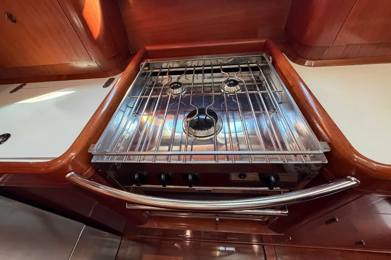 Nae Hassle Yacht Photos Pics Stainless steel stove in 2004 Beneteau 57 yacht kitchen, featuring wooden cabinetry.