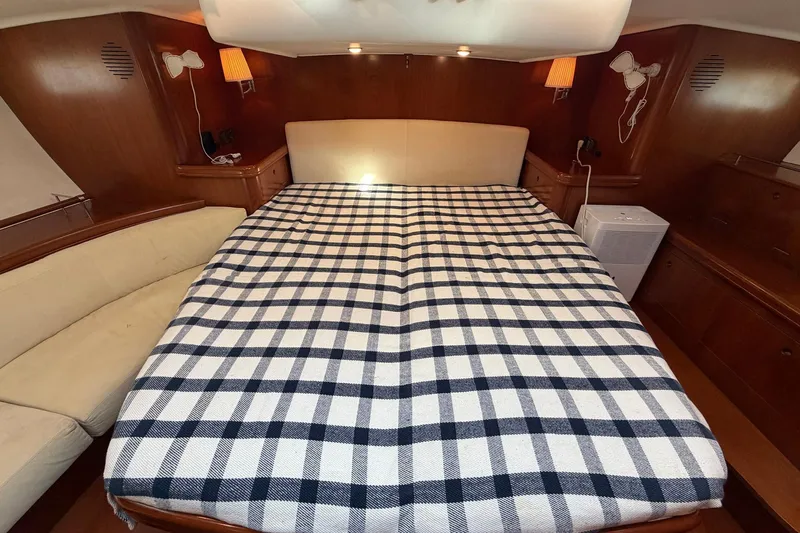 Nae Hassle Yacht Photos Pics Luxurious cabin interior of a 2004 Beneteau 57 yacht with a checkered bedspread.