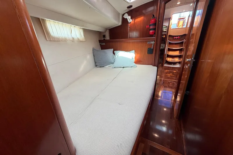 Nae Hassle Yacht Photos Pics 2004 Beneteau 57 yacht cabin with cozy bed, wooden interior, and soft lighting.
