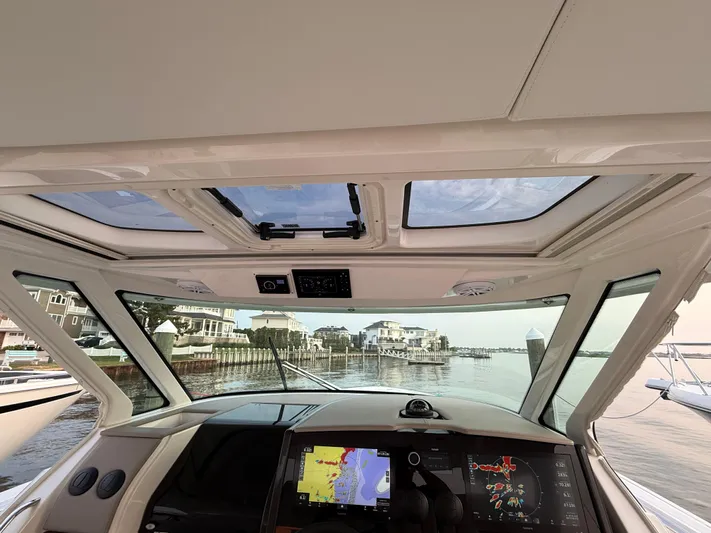  Yacht Photos Pics 2023 Tiara Yachts 43 LS helm view with navigation screens, overlooking a serene waterfront.