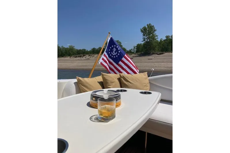 Lyman Zerga Yacht Photos Pics 2001 Sea Ray 380 Sundancer boat with drink on table, nautical flag, and scenic shoreline.