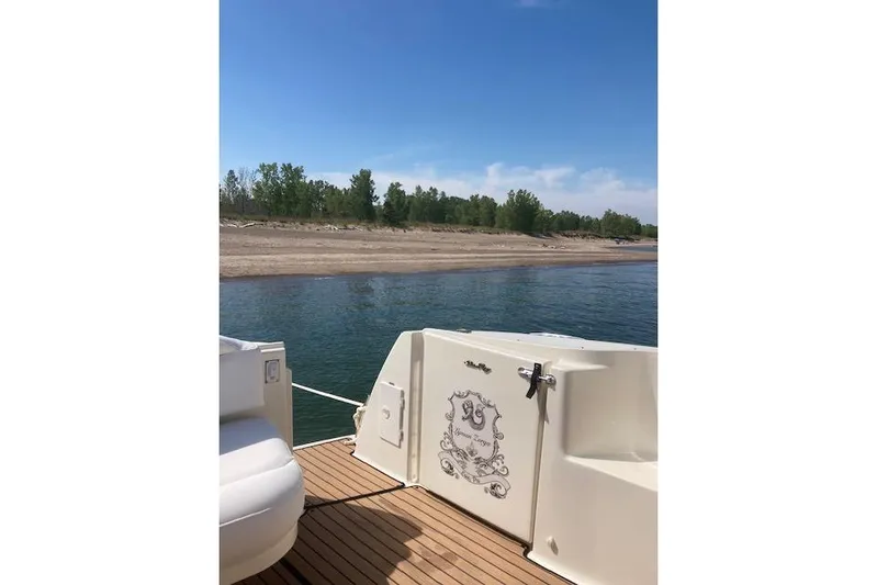 Lyman Zerga Yacht Photos Pics 2001 Sea Ray 380 Sundancer yacht on calm water near a sandy shore.