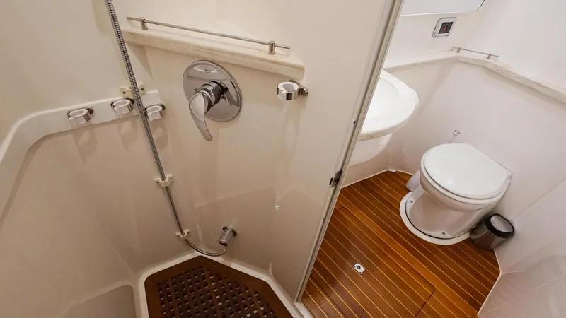 Audacious Yacht Photos Pics 2016 Intrepid 475 Panacea bathroom with shower, toilet, and wooden floor.