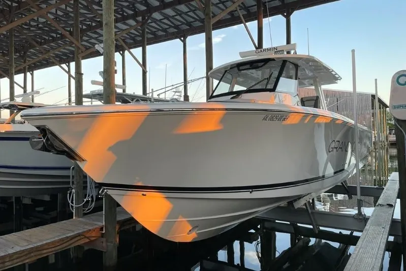  Yacht Photos Pics 2023 Pursuit S 358 Sport boat docked under a wooden shelter.