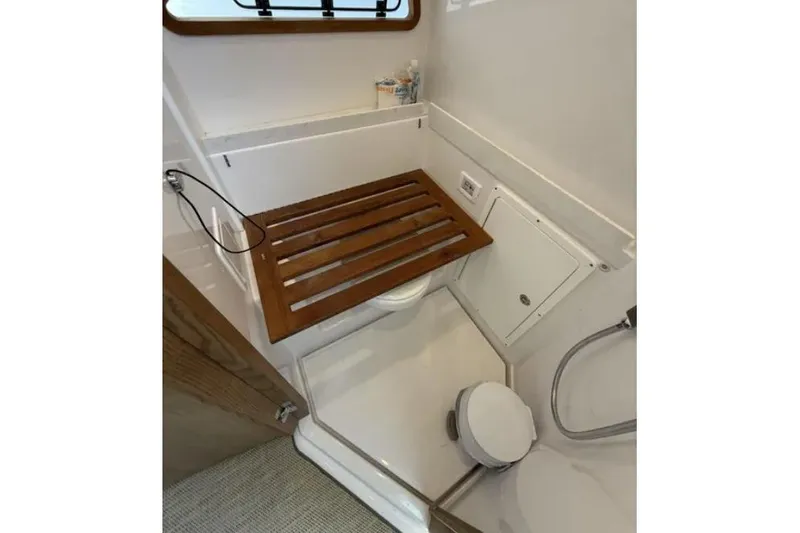  Yacht Photos Pics 2024 Bertram 39 CC boat bathroom with wooden seat and modern fixtures.