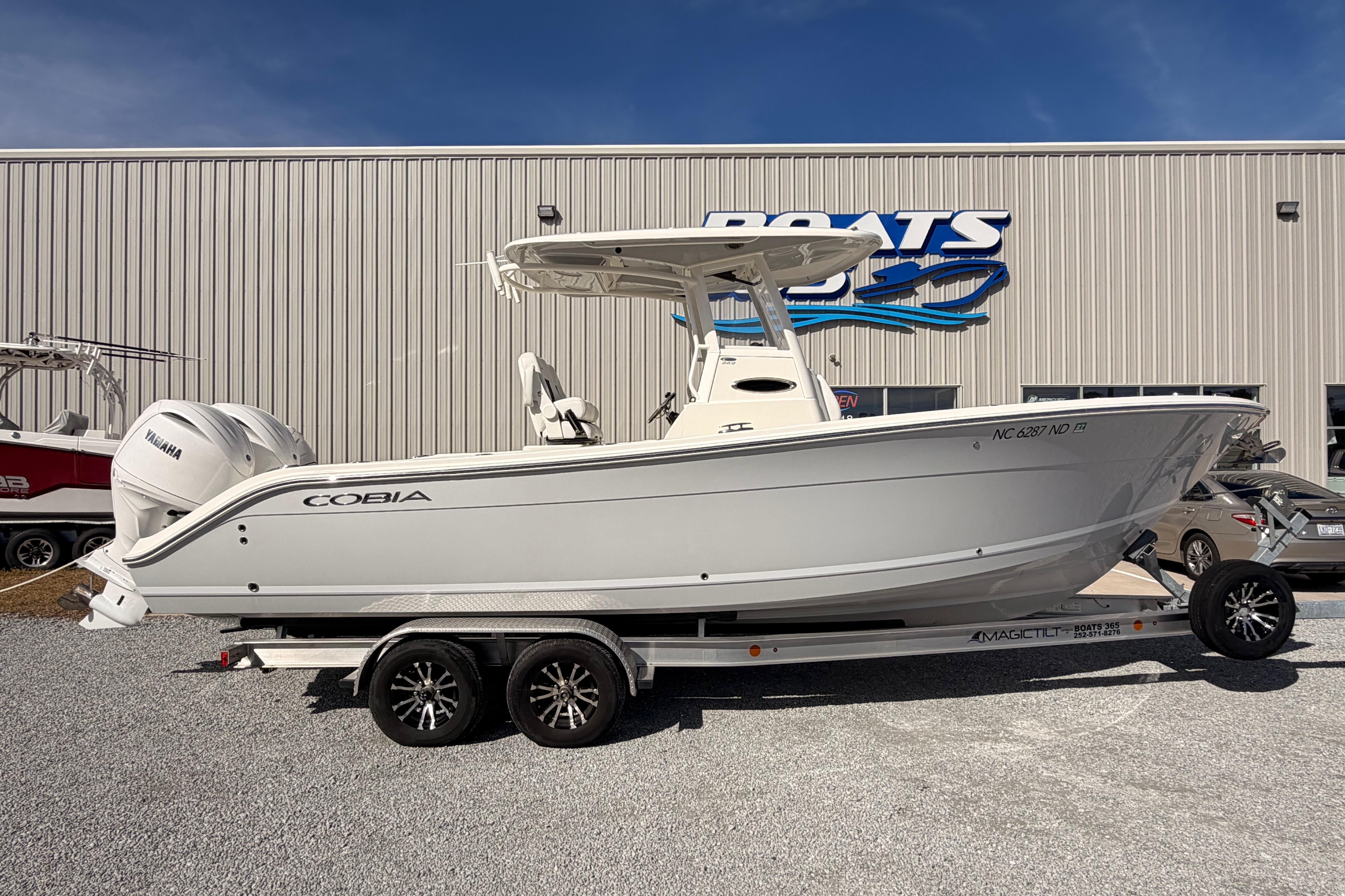 2024 Cobia 262 Center Console boat on trailer, parked outside dealership.