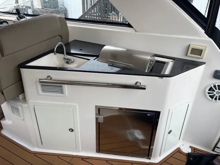  Yacht Photos Pics 2014 Regal 35 Sport Coupe boat kitchenette with sink, fridge, and storage cabinets.