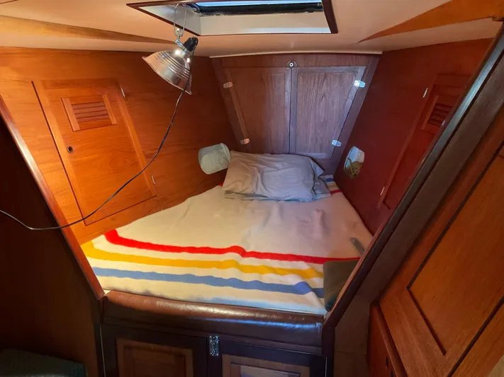  Yacht Photos Pics Cozy cabin interior of 1980 Kanter Staysail Cutter with wooden finish and striped bedding.