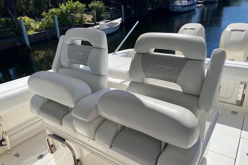  Yacht Photos Pics 2011 Boston Whaler 320 Outrage boat seats, white leather, docked by water.