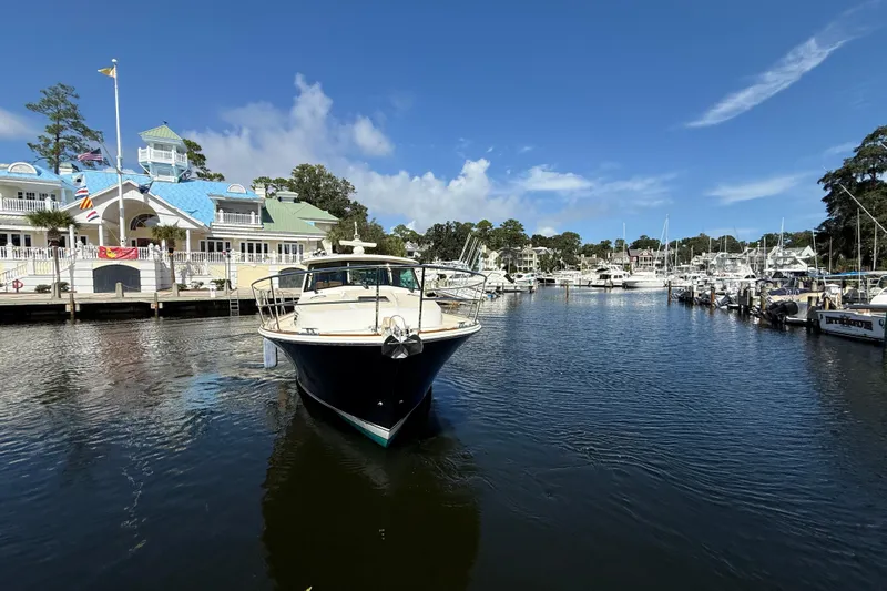 Strange Magic Yacht Photos Pics 2023 Sabre 43 Salon Express yacht docked at a scenic marina under a clear blue sky.