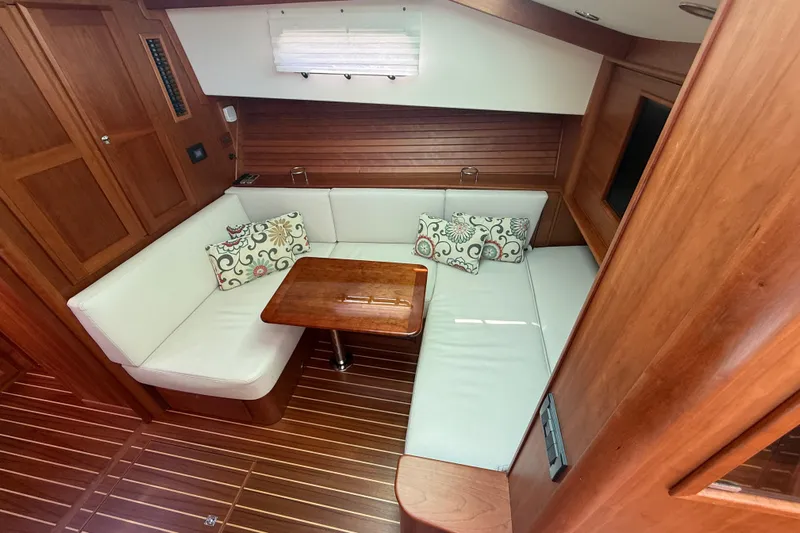 Strange Magic Yacht Photos Pics 2023 Sabre 43 Salon Express interior with wooden finish, white seating, and decorative pillows.