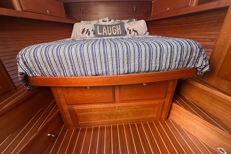 Strange Magic Yacht Photos Pics Cozy cabin interior of 2023 Sabre 43 Salon Express with striped bedding and wooden finish.